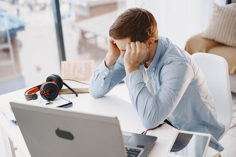 Profesional con estrés crónico por ambiente laboral tóxico frente a laptop